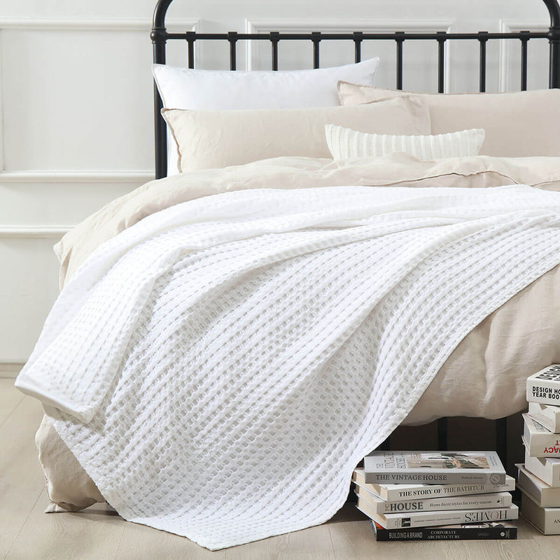 Temperature-regulating Cozy Bamboo Waffle Weave Throw Blanket in minimal white color used for layering on bed over duvet covers for a soft and cozy space relaxing and sleeping. Suitable for use on beds, couches and sofas for year-round comfort.