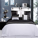 Black and white bedding set on a bed with decorative pillows and a nightstand.