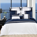 Navy and white bedding set with decorative pillows in a bedroom with ocean view.