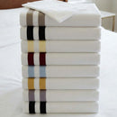 Stack of folded pillowcases with color stripes on a white surface