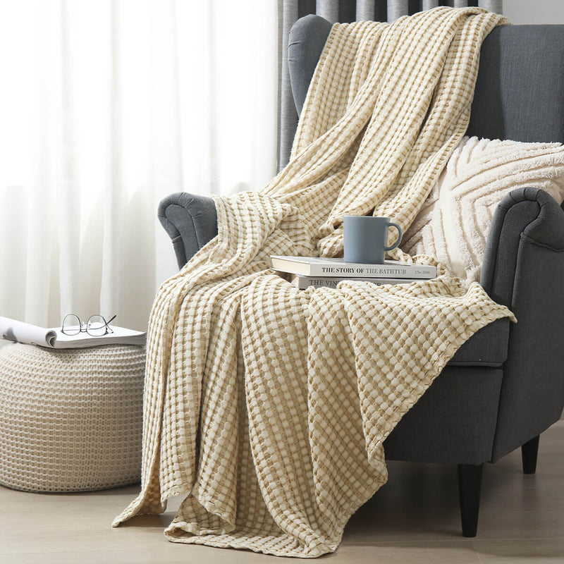 Temperature-regulating Cozy Bamboo Waffle Weave Throw Blanket in cream neutral beige color on armchair for a soft and cozy space for sitting, napping, or relaxing. Suitable for use on beds, couches and sofas for year-round comfort.