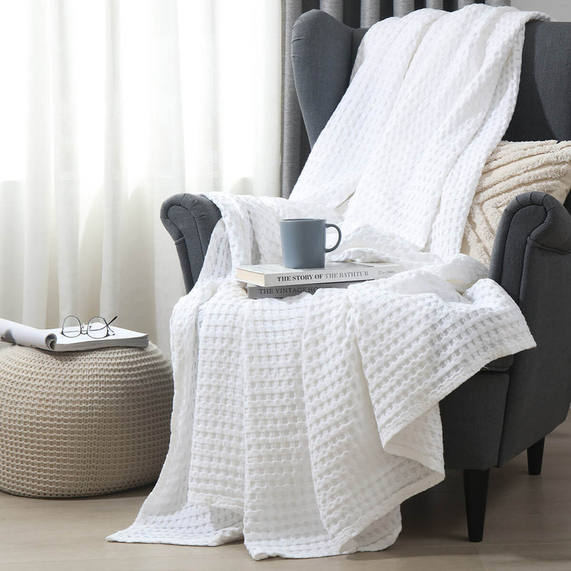 Temperature-regulating Cozy Bamboo Waffle Weave Throw Blanket in minimal white color on armchair for a soft and cozy space for sitting, napping, or relaxing. Suitable for use on beds, couches and sofas for year-round comfort.